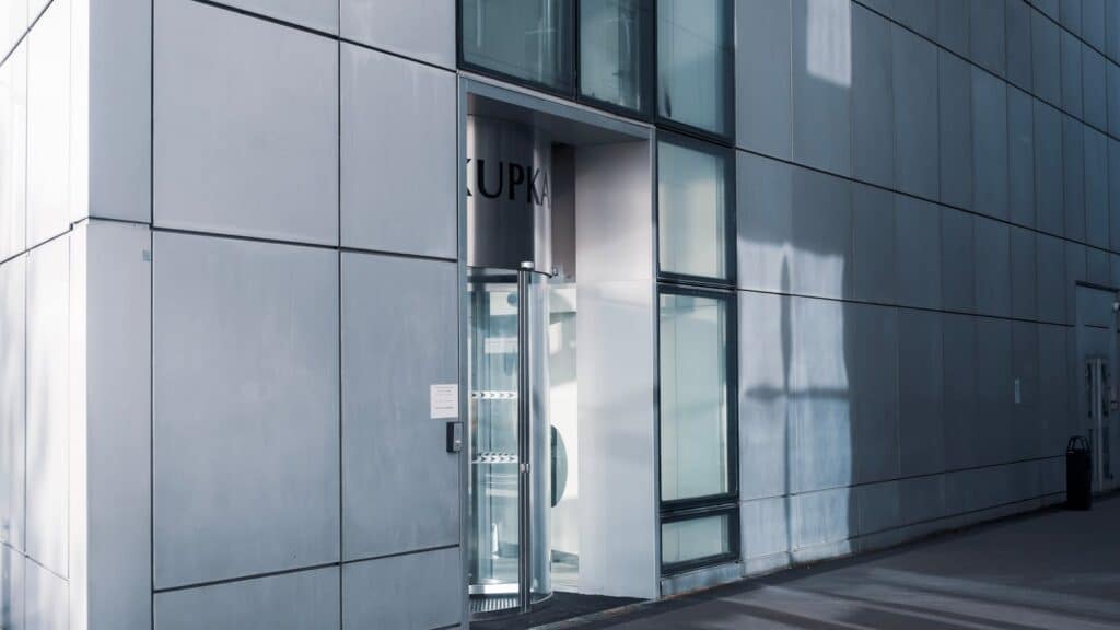 Sleek modern architecture featuring a glass entrance with reflective facade, showcasing contemporary design.