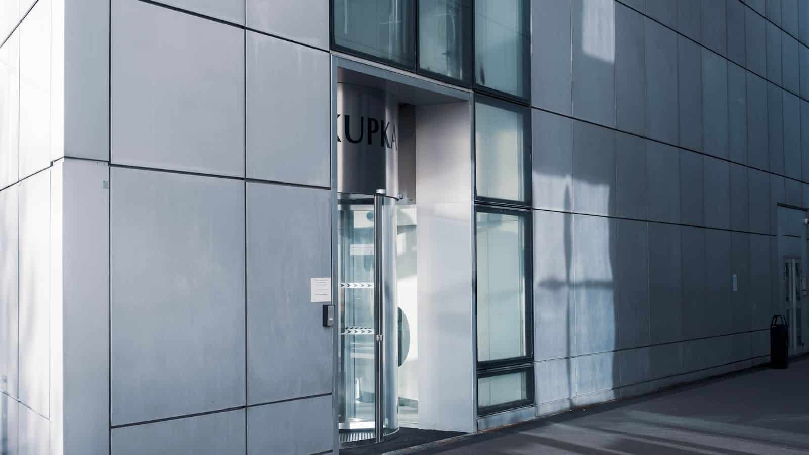 Sleek modern architecture featuring a glass entrance with reflective facade, showcasing contemporary design.