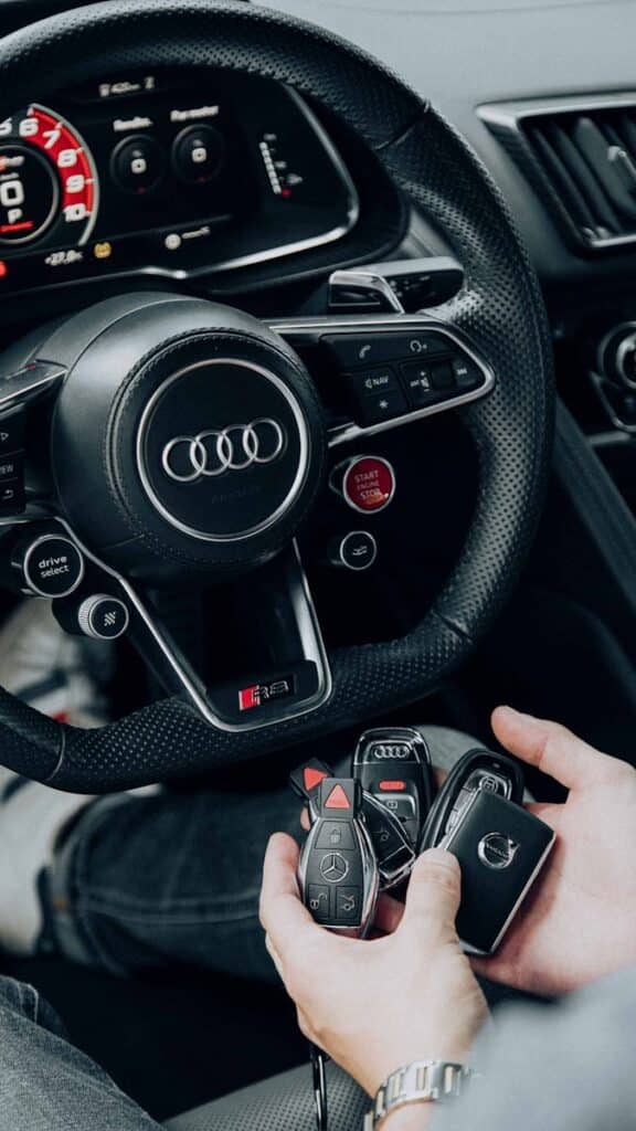 Detailed view of Audi car interior showcasing steering wheel and key fobs in hand for luxury vehicle lifestyle.