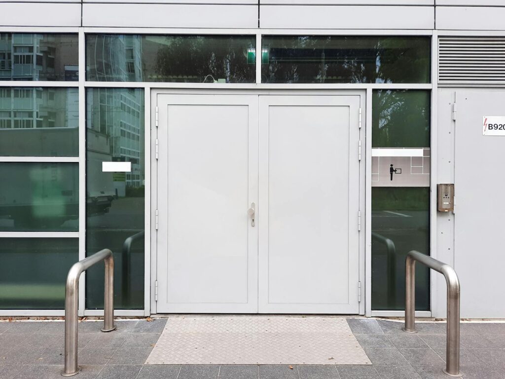 Front view of a modern glass building entrance featuring double doors and sleek design elements.