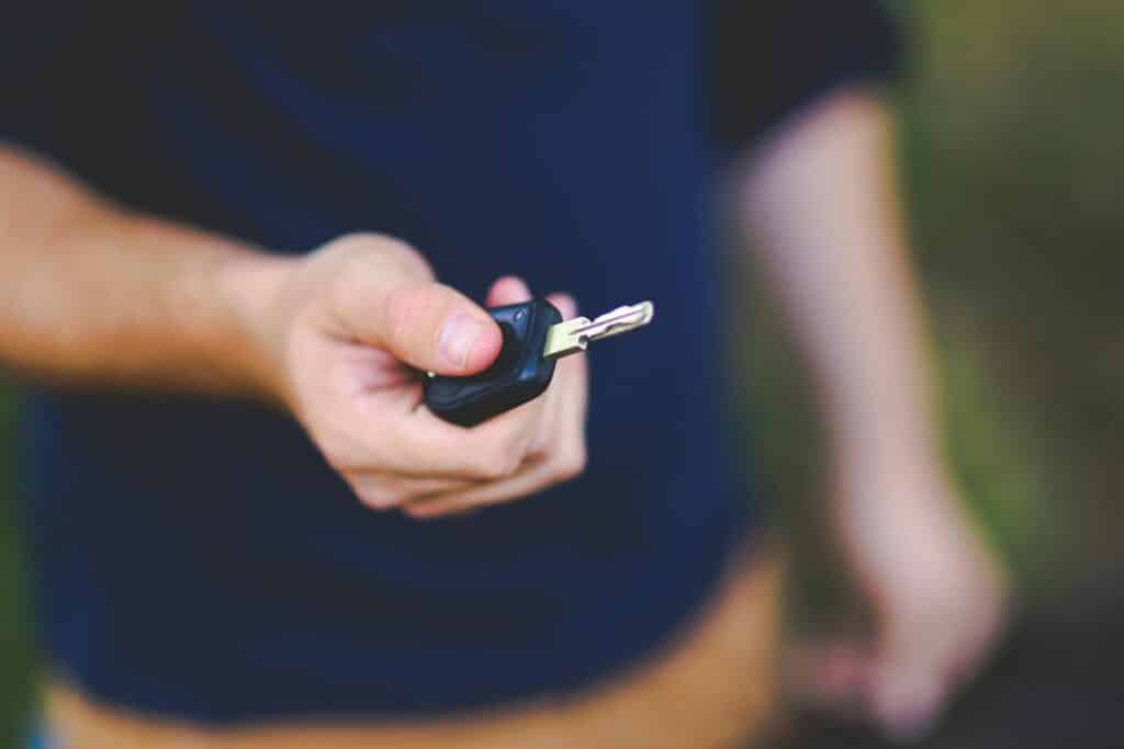 A hand holding a car key outdoors, emphasizing security and control.