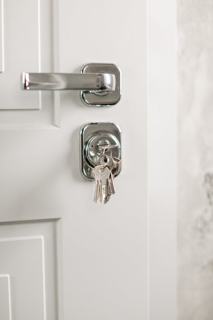 Close-up of a modern silver door handle with keys hanging in the lock, symbolizing security.