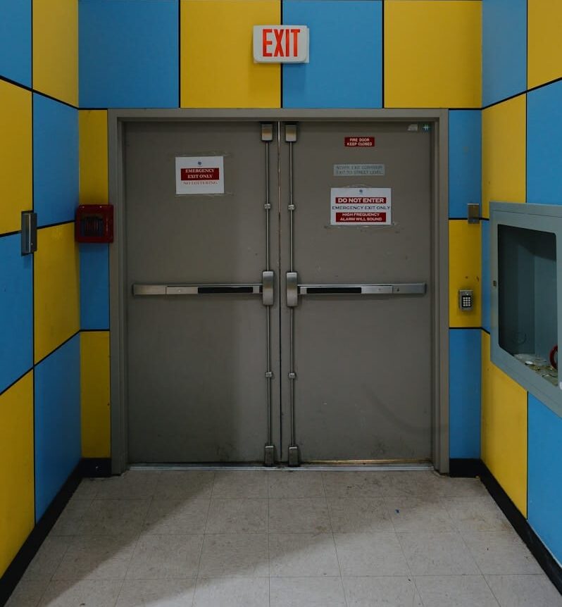 An exit door is framed by blue and yellow tiles.